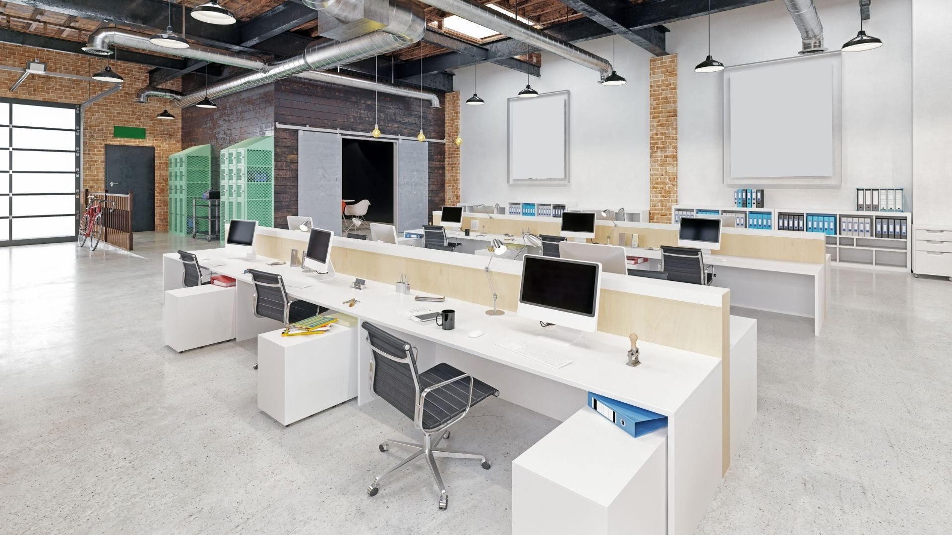 Modern open-plan office with workstations, exposed brick, and industrial lighting