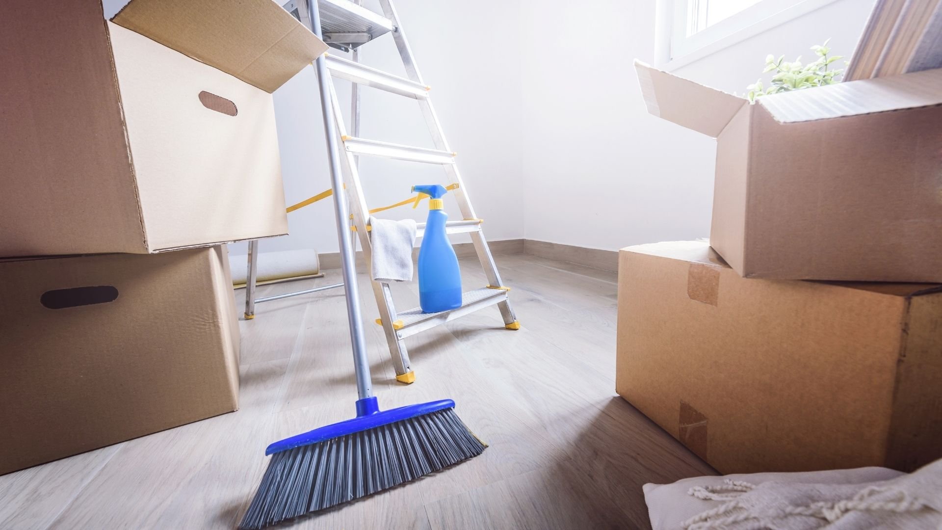 Moving day scene with cardboard boxes, cleaning supplies, and stepladder