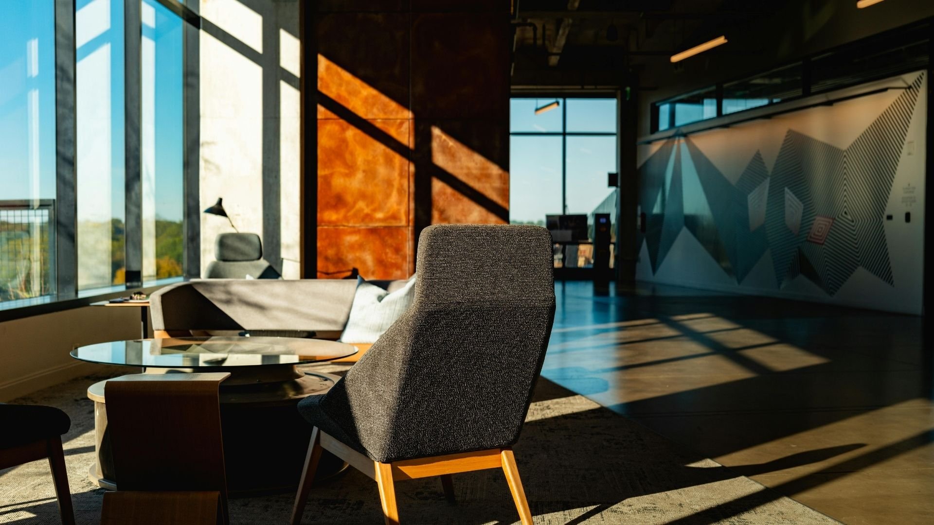 Modern office interior with sunlight casting shadows on gray chairs