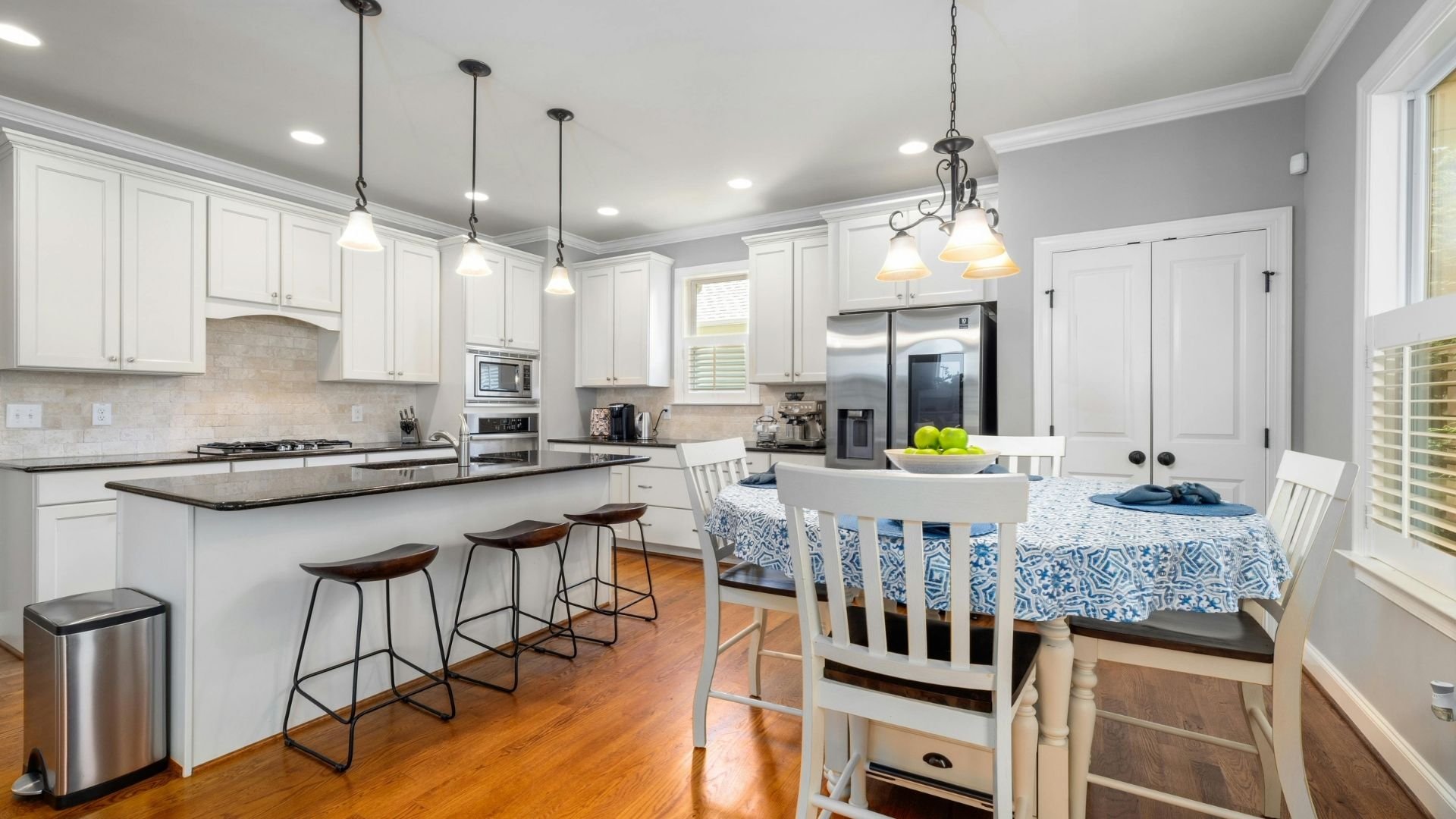 Modern white kitchen with island, bar stools, and blue dining table